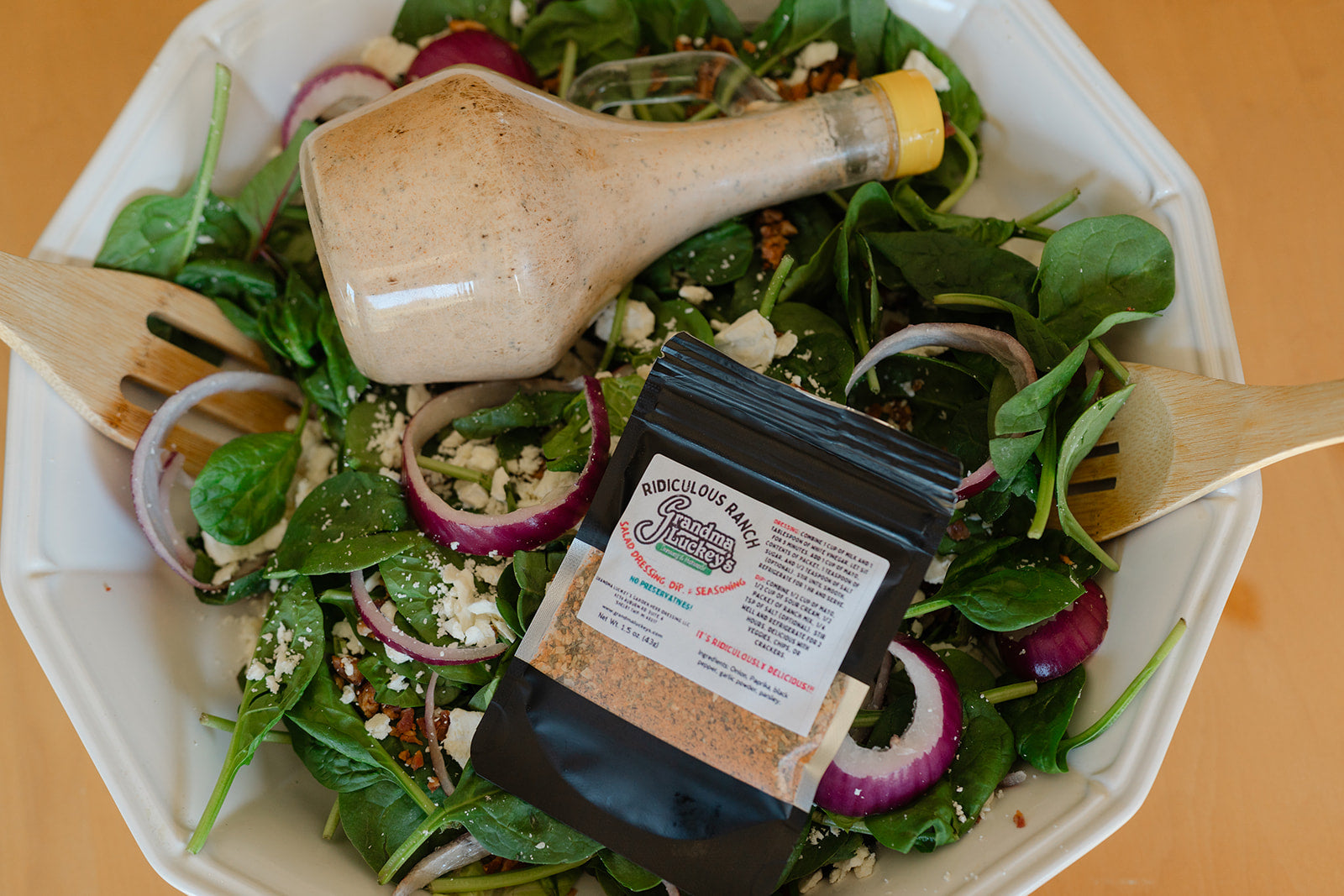 Salad with a bottle of dressing and a package of seasoning on a white plate.
