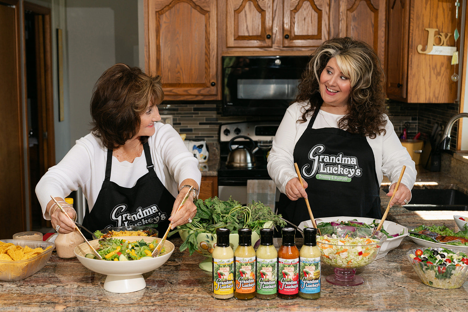 Two women (the owners) preparing food in a kitchen with 'Grandma Lucky's' aprons.